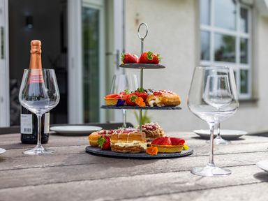 A tiered stand with pastries and strawberries on a wooden table with wine glasses and a champagne bottle outside a building at Parc Y Deri in Rhos-y-garth near Aberystwyth