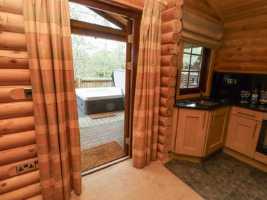 A kitchen with wooden cabinets and a sink next to a door leading to a deck with a hot tub at 24 Lakeside Drive Felton