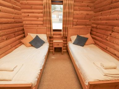 A bedroom with two single beds a window with curtains and a nightstand at 24 Lakeside Drive in Felton