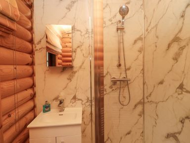 A bathroom with a white sink cabinet and shower area with marble walls at 24 Lakeside Drive in Felton