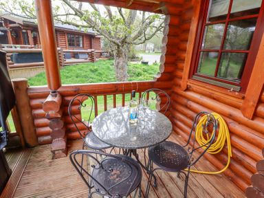 A porch with a round table three metal chairs a bottle of wine and two glasses at 24 Lakeside Drive in Felton