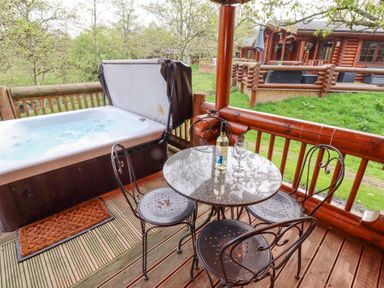 A patio with a hot tub table with wine bottle and glasses and metal chairs at 24 Lakeside Drive in Felton