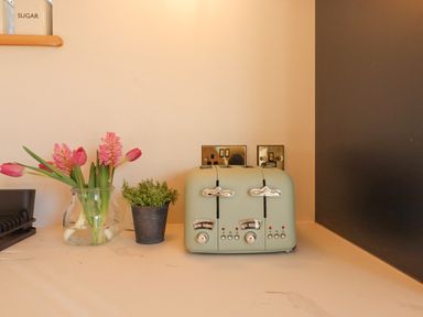A kitchen counter with a toaster flowers in a glass jar and a small potted plant at Church Farm Dairy Cadbury near Thorverton