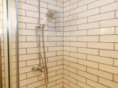 A shower area with tiled walls and a handheld showerhead at Church Farm Dairy in Cadbury near Thorverton