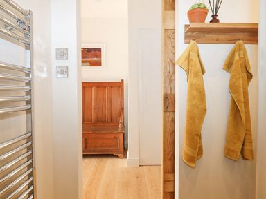 A hallway with yellow towels hanging on wooden hooks and a wooden chair in the background at Church Farm Dairy Cadbury near Thorverton