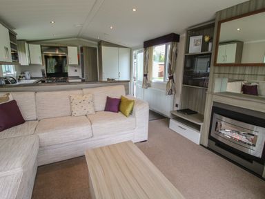 A living room with a sectional sofa and pillows next to a fireplace and kitchen at Swan in Shobdon