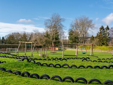 A playground with swings and tires at Swan in Shobdon