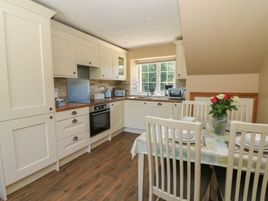 A kitchen with cabinets and a dining area at Felin Gogoyan Tregaron