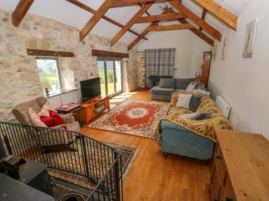 A living room with wooden beams stone walls sofas and a television at Bryn Nante Morvil near Maenclochog