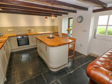 A kitchen with wooden countertops a central island and black stone flooring at Bryn Nante in Morvil near Maenclochog