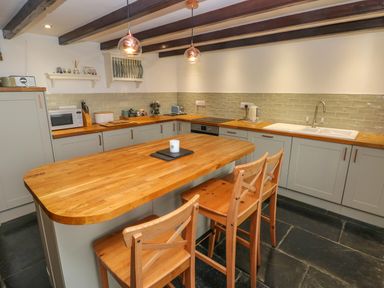 A kitchen with wooden countertops wooden island and chairs under ceiling beams at Bryn Nante in Morvil near Maenclochog