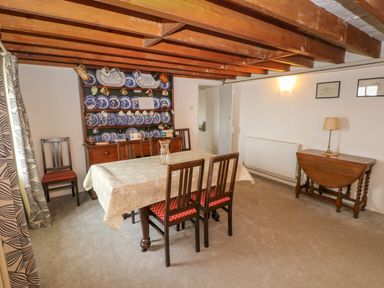 A dining room with a table and chairs and a wooden shelf with plates and cups at Bryn Nante in Morvil near Maenclochog