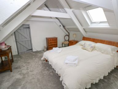 A bedroom with a bed a bedside table a chest of drawers a chair and a small wooden table at Bryn Nante in Morvil near Maenclochog