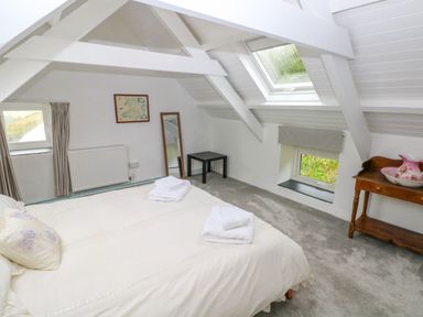 A bedroom with a bed folded towels a framed map a standing mirror a small table and a wooden console table with a ceramic basin at Bryn Nante in Morvil near Maenclochog