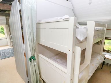 A bedroom with a white wooden bunk bed next to a window with a table and chairs at Bryn Nante in Morvil near Maenclochog