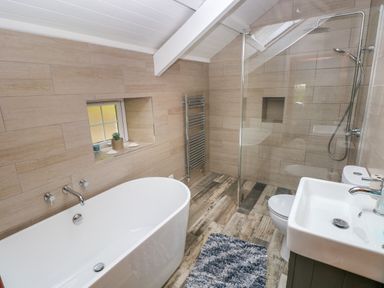 A bathroom with a bathtub a shower a sink a toilet and a window at Bryn Nante in Morvil near Maenclochog