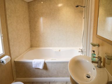 A bathroom with a bathtub shower sink mirror and towel at Daisy in Eardisland