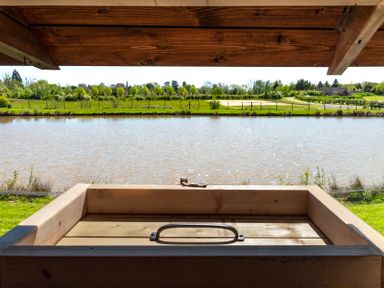 A view of a pond and greenery from a wooden structure at Daisy in Eardisland