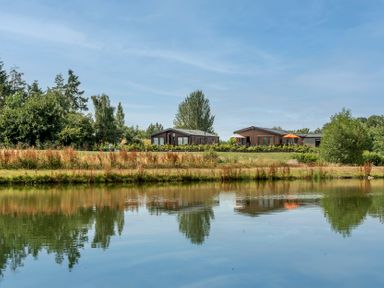 A view of houses and trees reflected in water at Daffodil in Eardisland