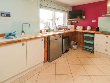 A kitchen with a sink dishwasher toaster kettle and television at Coast Cottage in Bamburgh