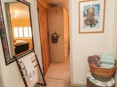 A hallway with a mirror towel rack and a basket of towels with a framed picture on the wall at Coast Cottage in Bamburgh
