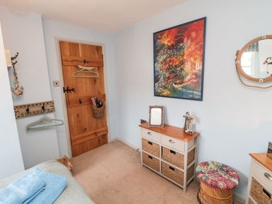 A bedroom with a wooden door wicker basket and dresser with wicker drawers at Coast Cottage in Bamburgh