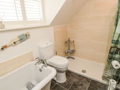 A bathroom with a bathtub toilet shower and nautical themed decor at Coast Cottage in Bamburgh