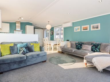 A living room with two sofas, dining table with chairs, and kitchen area at Lake View Lodge in Tallington
