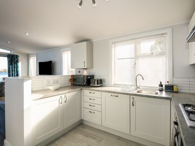 A kitchen with white cabinets a microwave toaster and a sink at Lake View Lodge in Tallington