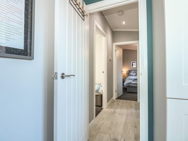 A hallway with open doors leading to bedrooms with beds and nightstands at Lake View Lodge in Tallington
