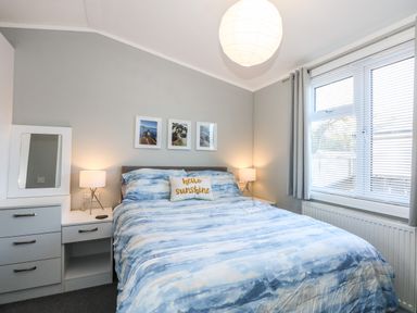 A bedroom with a bed blue patterned bedding bedside tables lamps and window blinds at Lake View Lodge in Tallington