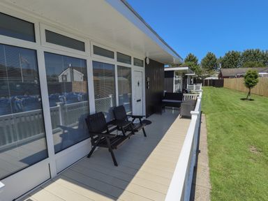 A porch with outdoor chairs and a green lawn beside it at 114 Cherry Park in Chapel St Leonards