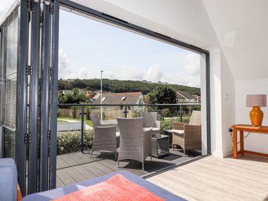 A seating area with wicker chairs and a glass table on a balcony outside a living room at Pebble Ridge View in Westward Ho
