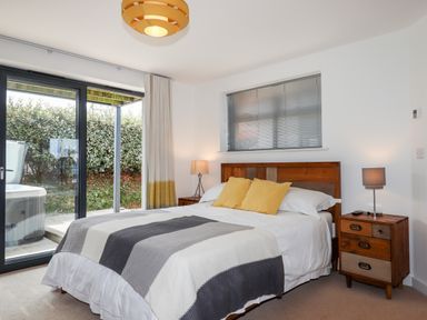 A bedroom with a bed and bedside tables with lamps and sliding glass door leading outside at Pebble Ridge View in Westward Ho