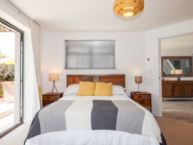 A bedroom with a bed with yellow pillows lamps on wooden bedside tables and a view into another room at Pebble Ridge View in Westward Ho