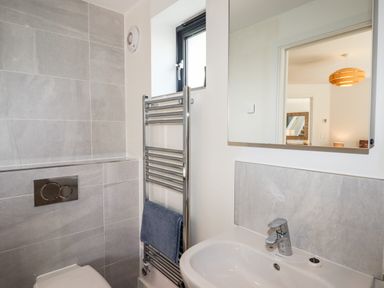 A bathroom with a sink mirror toilet and heated towel rail with a towel at Pebble Ridge View in Westward Ho