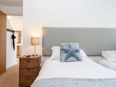 A bedroom with two beds a wooden bedside table with a lamp and a cushion with a starfish at Pebble Ridge View in Westward Ho