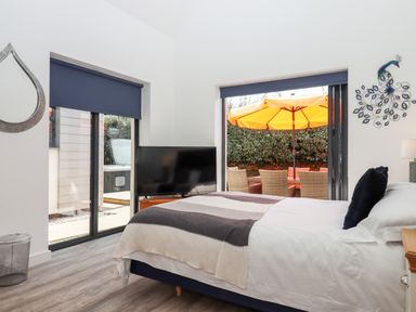 A bedroom with a bed a television a mirror and sliding glass doors leading to an outdoor patio with a yellow umbrella at Pebble Ridge View in Westward Ho