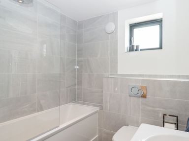 A bathroom with a bathtub shower toilet and a window at Pebble Ridge View in Westward Ho