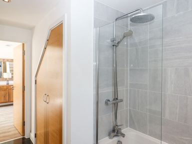 A bathroom with a shower and bathtub next to a hallway with wooden doors at Pebble Ridge View in Westward Ho