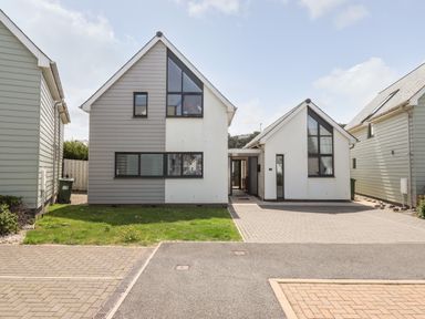 A modern detached house with a driveway and lawn at Pebble Ridge View in Westward Ho