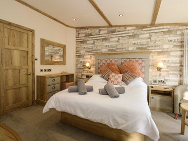 A bedroom with a bed with pillows and towels a wooden door a desk with drawers a mirror and a nightstand at 18 Woodlands Retreat in Tattershall