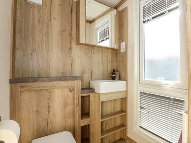 A bathroom with a sink cabinet mirror wooden walls and window blinds at 18 Woodlands Retreat in Tattershall