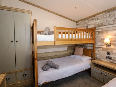 A bedroom with wooden bunk beds a wardrobe and a small cabinet at 18 Woodlands Retreat in Tattershall