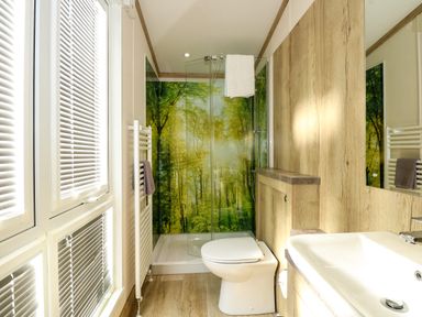 A bathroom with a toilet sink and shower featuring a forest mural at 18 Woodlands Retreat in Tattershall