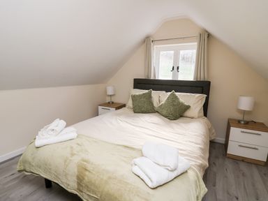 A bedroom with a bed with pillows and folded towels bedside tables with lamps and a window at Railway Station Cottage in New Radnor near Kington