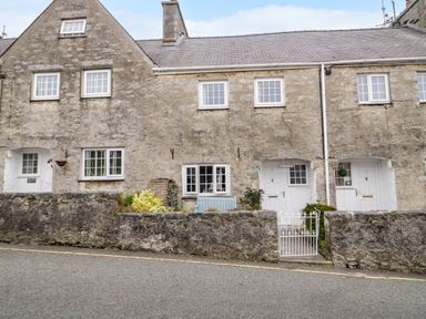 Stone cottages with white doors and windows and a small garden with a bench behind a low stone wall at 3 Moranedd Moelfre