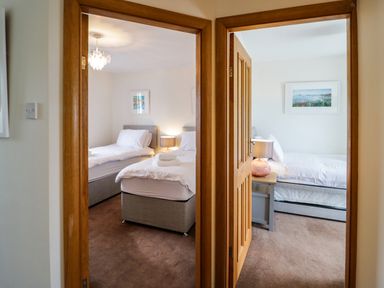 Two bedrooms with single beds bedside tables and lamps at 3 Moranedd Moelfre