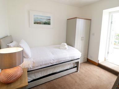 A bedroom with a single bed bedside table with lamp wardrobe and a door at 3 Moranedd Moelfre