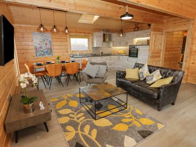 A living room with a sofa armchair coffee table dining table chairs and kitchen at Height End Farm Log Cabin Rossendale near Bacup